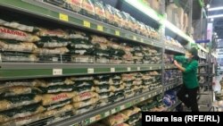Дүкен сөресіне азық-түлік қойып жатқан сауда қызметкері. Азаттық архивіндегі фото.