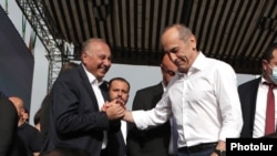 Prominent Armenian surgeon Armen Charchian (L) is being greeted by former President Robert Kocharian, leader of the opposition Hayastan alliance, during a rally in Yerevan, May 9, 2021.