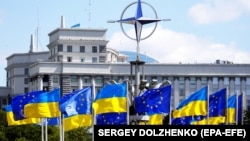 Steaguri ale Ucrainei și Uniunii Europene, sub emblema NATO, în Piața Europei din Kiev (iulie 2023) 