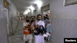 Pakistan -- A man carries a child, who was injured in a suicide bomb attack, to the Lady Reading Hospital for treatment in Peshawar, 21Jun2013
