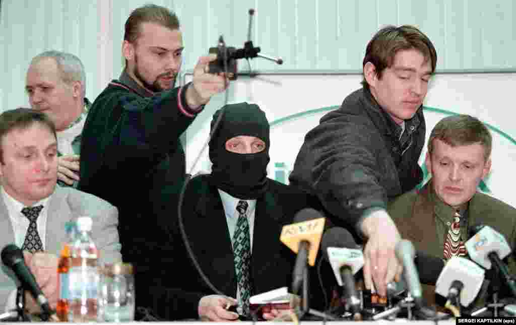 Conferința de presă a trei ofițeri FSB, la agenția Interfax de la Moscova, 17 noiembrie 1998. Fostul agent Mihail Trepașkin (stânga), un coleg purtând o mască pentru a-și proteja identitatea (centru) și colonelul Litvinenko (dreapta) i-au acuzat pe șefii lor de la FSB că au ordonat răpiri și asasinate, inclusiv o tentativă de a-l ucide pe politicianul și miliardarul Boris Berezovski.