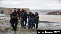 Afghan security forces carry children after flood affected their homes in Arghandab district of Kandahar Province on March 2.