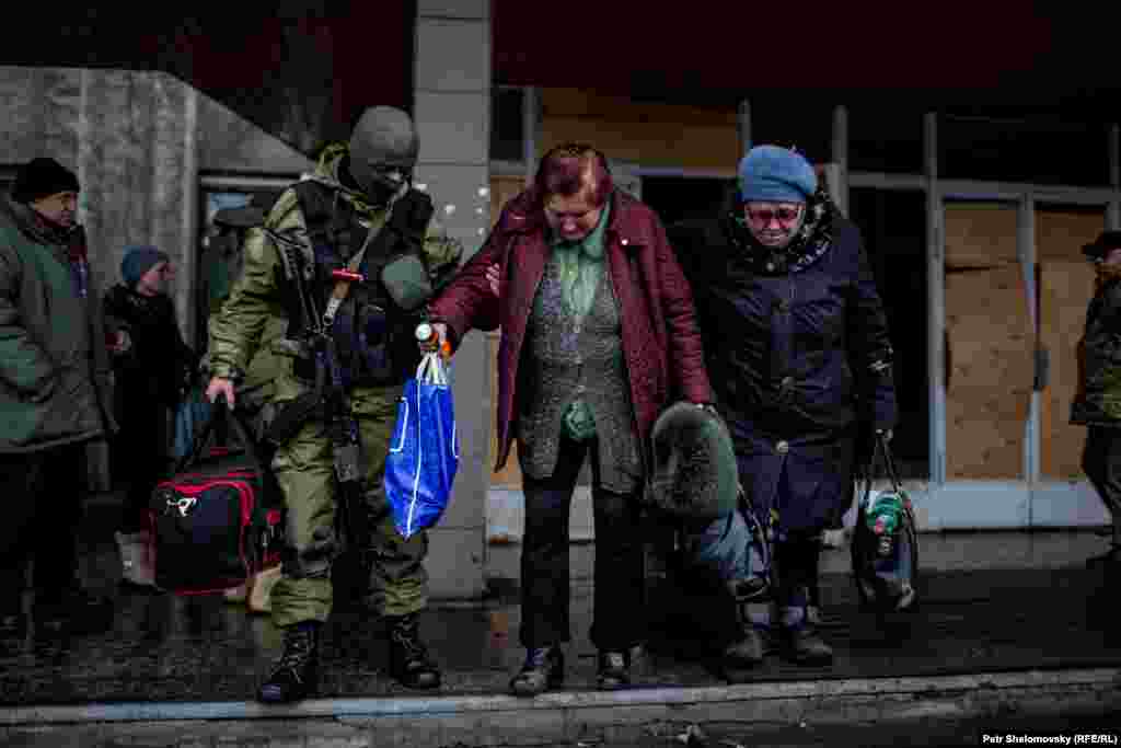 Vojnik pomaže stanovnicima sa njihovim stvarima dok traje evakuacija.