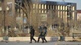 Полицейский патруль на фоне поврежденных зданий. Жанаозен, 19 декабря 2011 года.